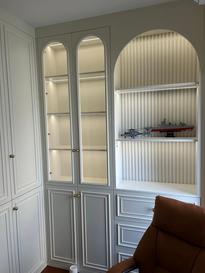 Classic white built-in display cabinet with arched glass doors, an illuminated fluted niche and brass knobs in a Singapore HDB living room